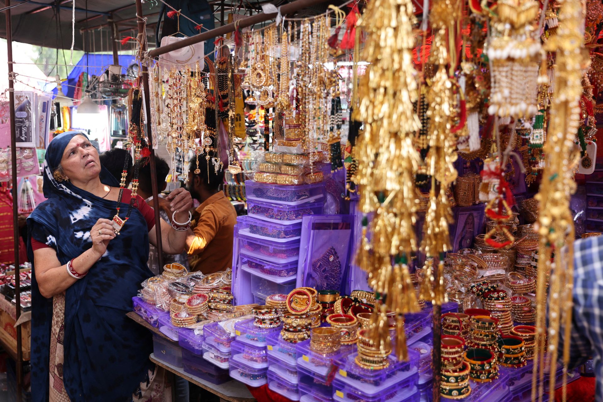 Kamlaben Ashokbhai Patni adjusts imitation jewellery at a stall in a market in Ahmedabad, India, April 30, 2023. Photo: Reuters
