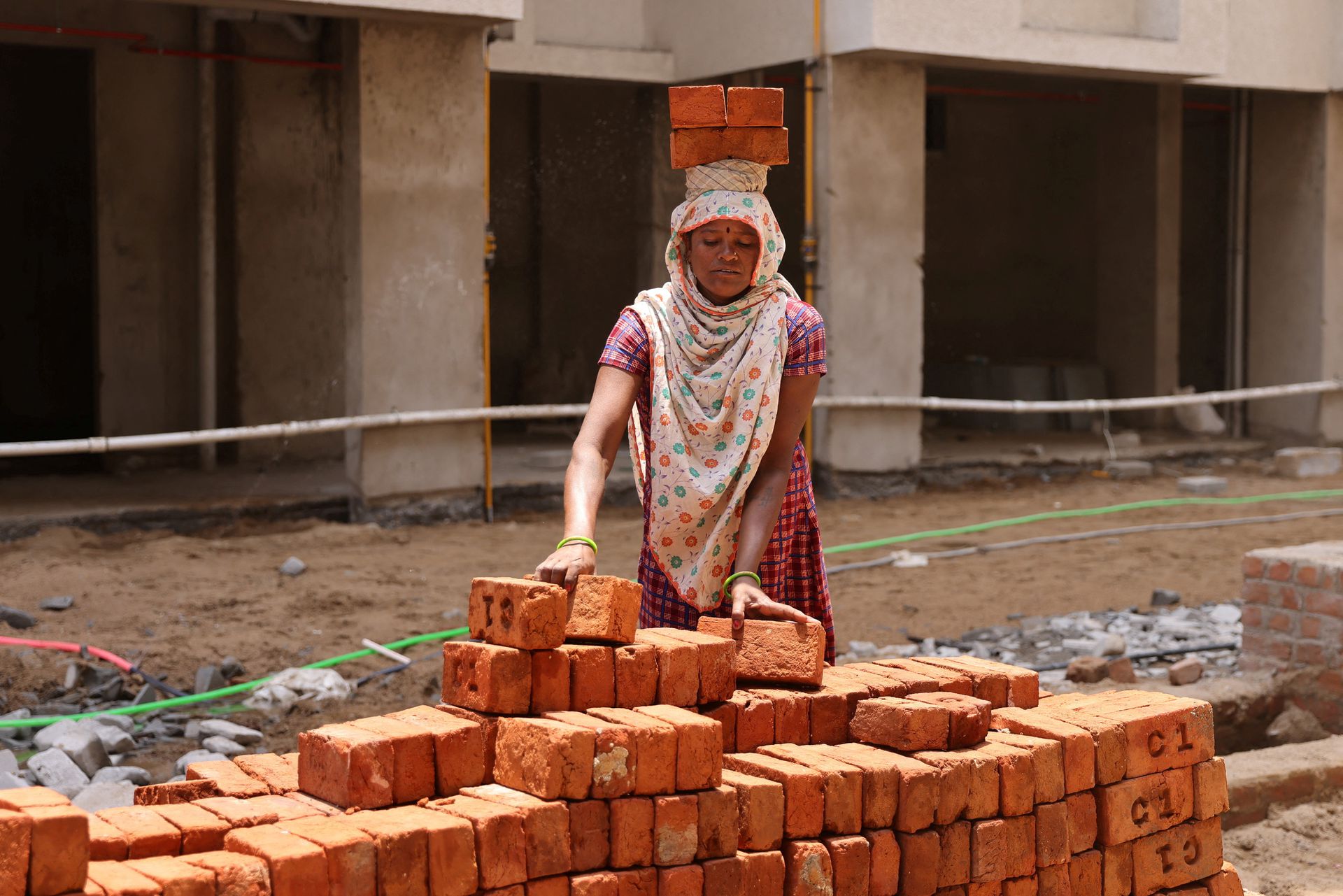 A woman carries bricks at a construction site in Ahmedabad, India, April 28, 2023. Photo: Reuters