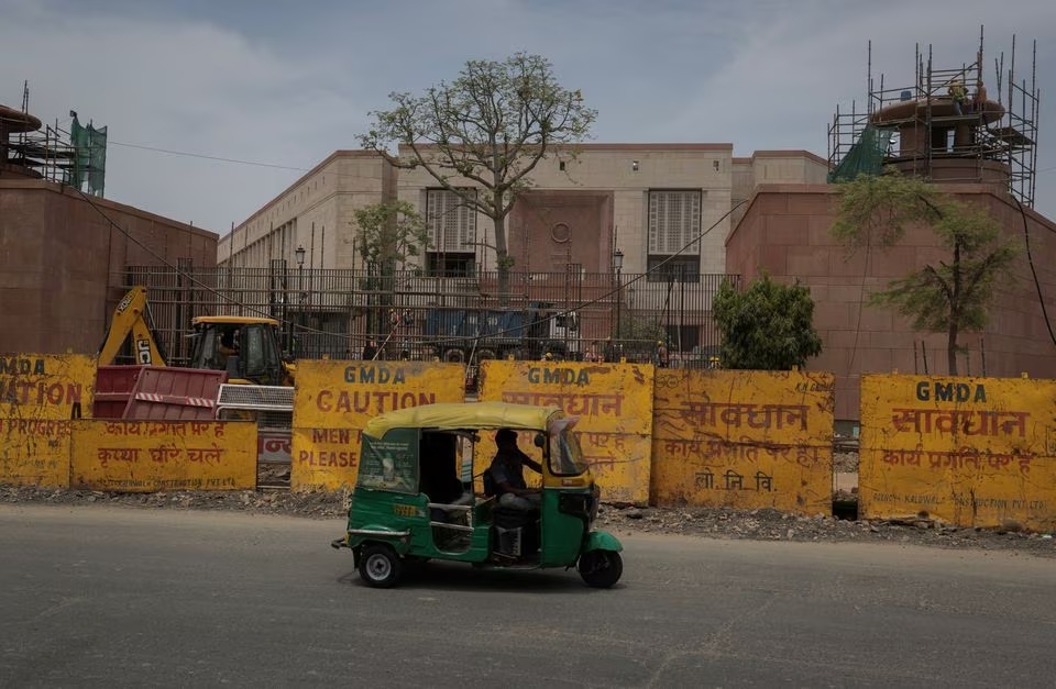 An auto rickshaw drives pasts in front of the under construction site of the new parliament building in New Delhi, India, May 23, 2023. Photo: Reuters