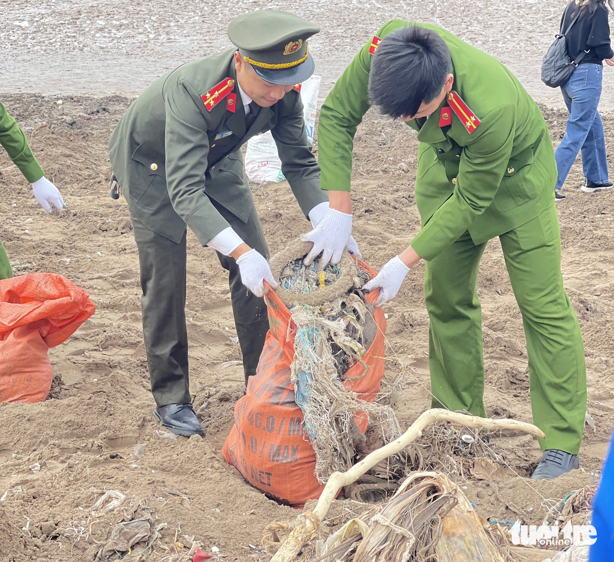 Police officers collect waste along the beach of Giao Hai Commune. Photo: Ha Thu / Tuoi Tre