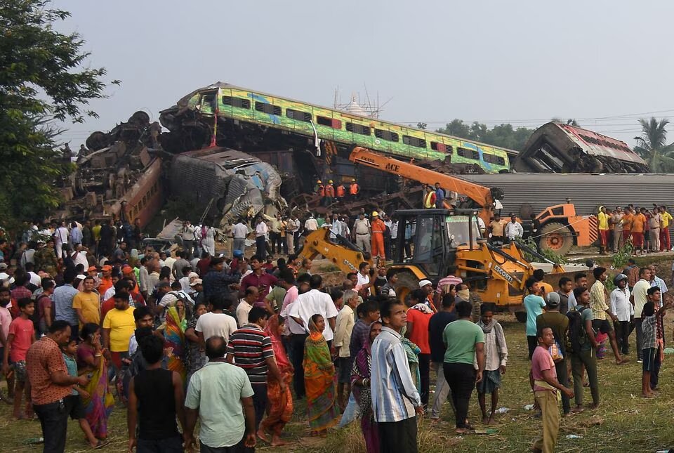 People stand next to damaged coaches after two passenger trains collided in Balasore district in the eastern state of Odisha, India, June 3, 2023. Photo: Reuters