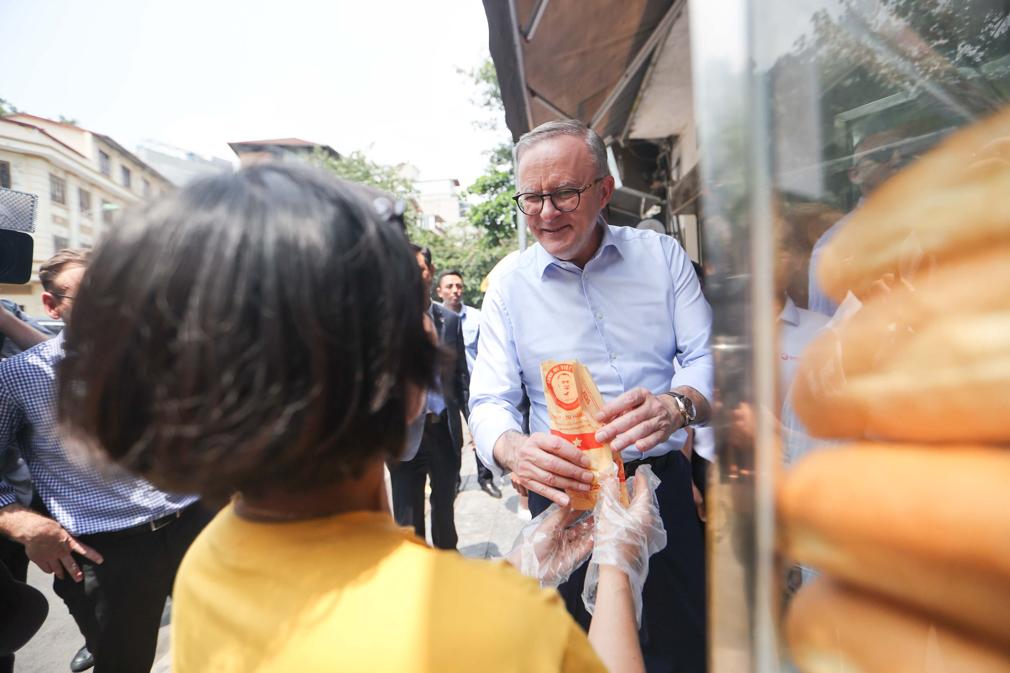 A staff member of a banh mi stall gives banh mi to PM Albanese