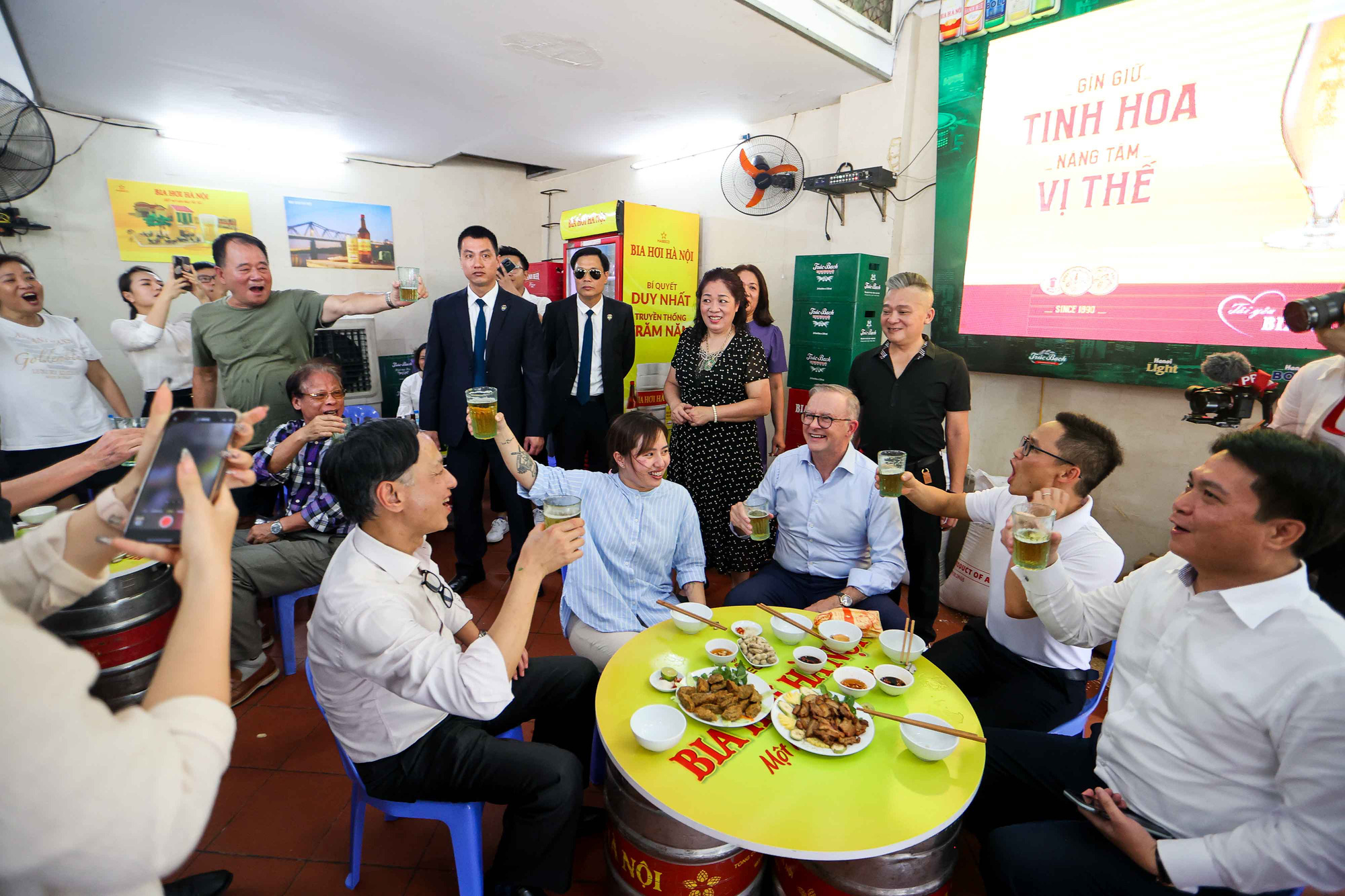 PM Albanese jointly says "Mot, hai, ba, Do!" (one, two, three, Cheers!) and chats with people drinking beer in the shop