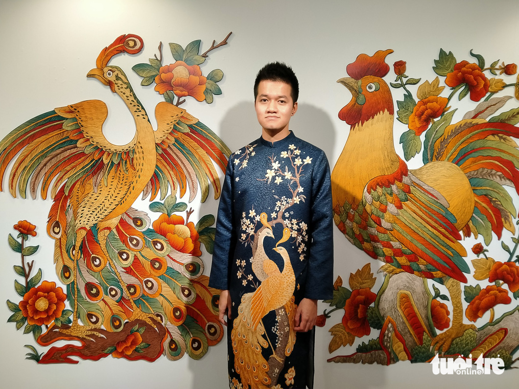 Vietnamese artist Xuan Lam poses for a photo with his ‘Thien ha thai binh’ painting (L). Photo: Thien Dieu / Tuoi Tre