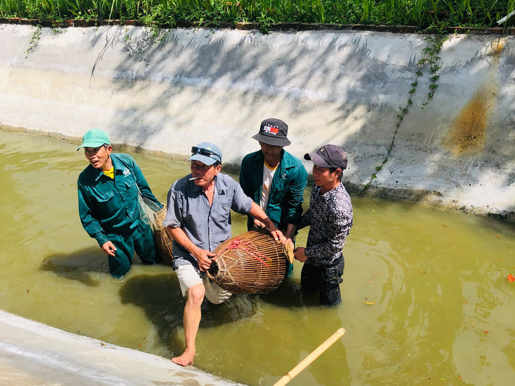 Some employees at a tourist site in Khanh Hoa Province fish an endangered monitor out of a lake