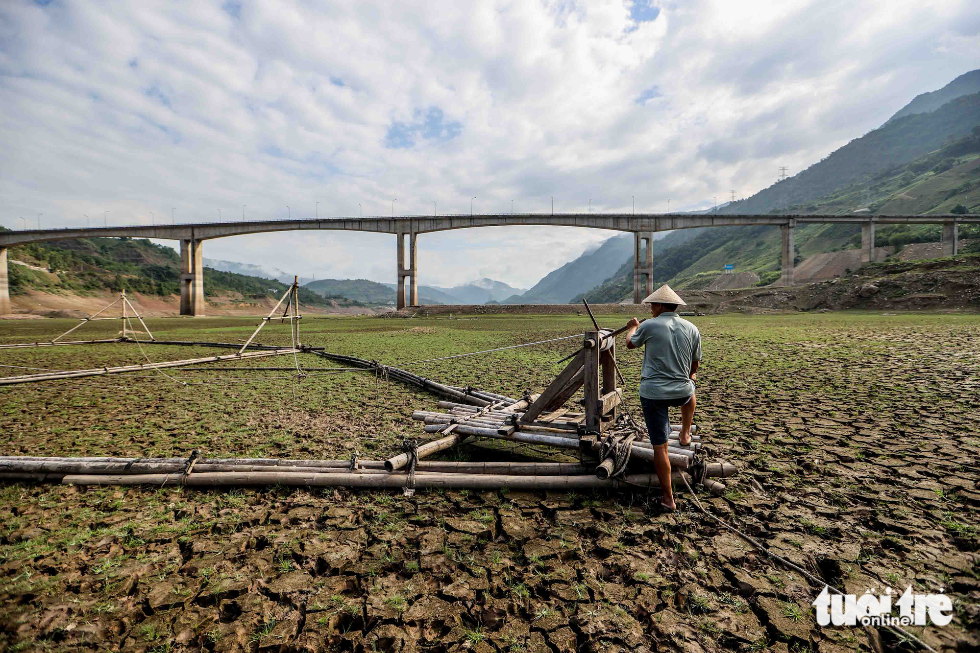 Vang Van Vuong, a local inhabitant in the Son La hydropower reservoir area, stands next to his family's lift net on the dried-up reservoir bed. Photo: Nguyen Khanh / Tuoi Tre