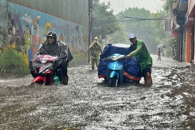 Commuters wade through a flooded section of Bui Xuong Trach Street in Thanh Xuan District. Photo: Thanh Nien (Young People) newspaper