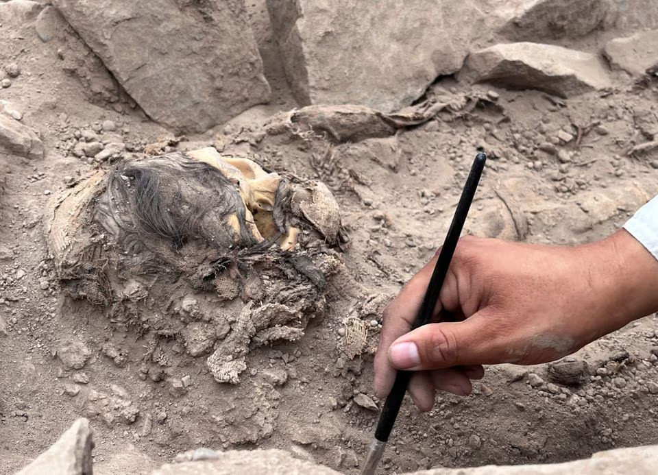 An archaeologist works at the excavation site of a pre-Hispanic burial next to a mummy believed to be from the Manchay culture, which developed in the valleys of Lima between 1,500 and 1,000 BCE, in Lima, Peru, June 14, 2023. Photo: Reuters