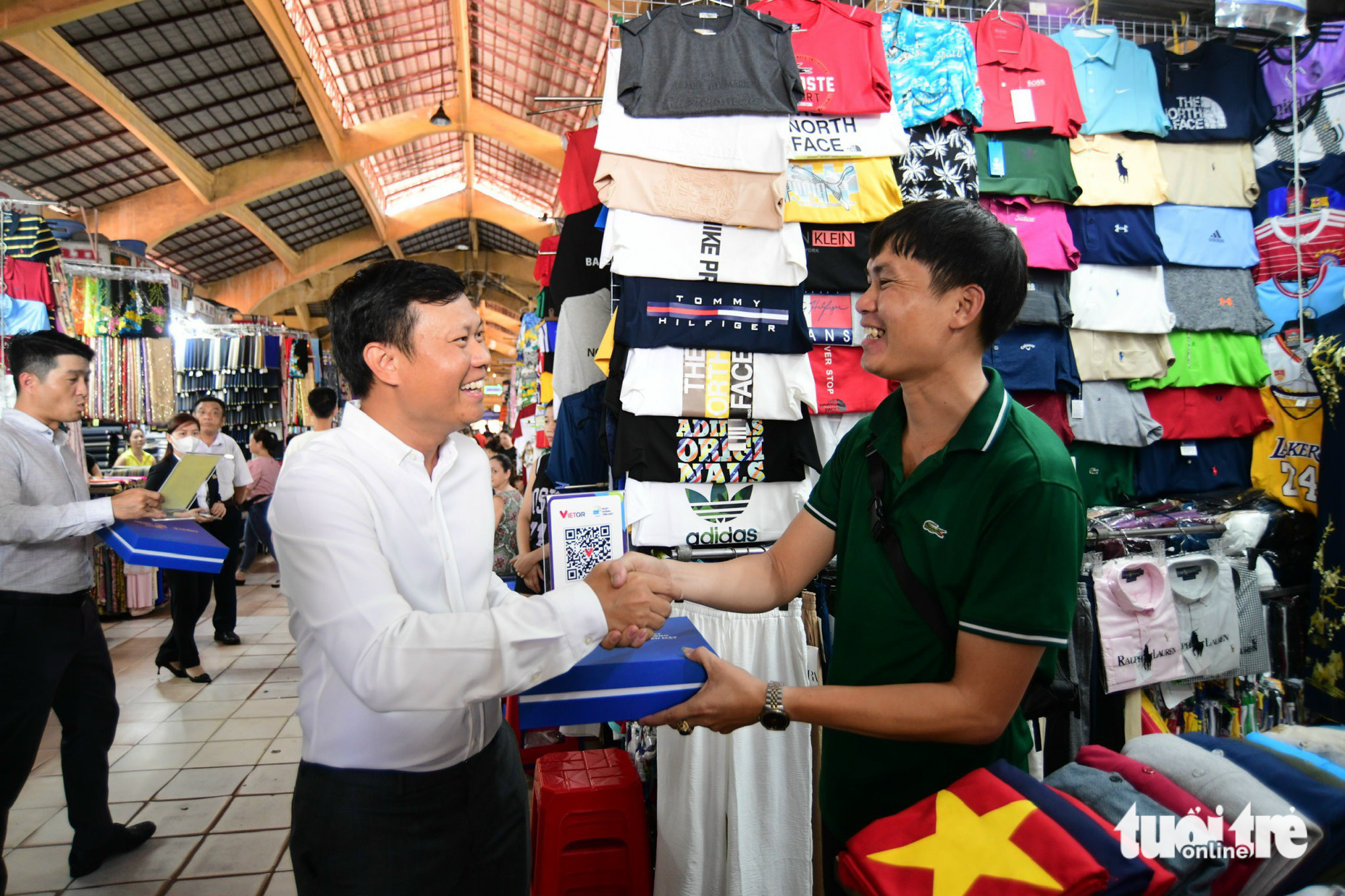 Nguyen Duc Huynh (L), head of the National Payment Corporation of Vietnam’s (NAPAS) office in Ho Chi Minh City, presents a VietQR code to a vendor at Ben Thanh Market. Photo: Quang Dinh / Tuoi Tre