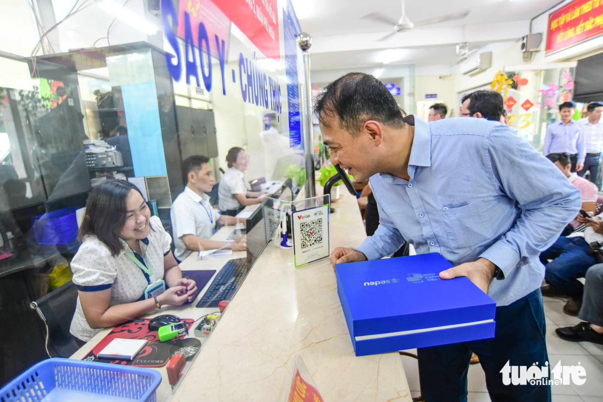 A representative of the National Payment Corporation of Vietnam (NAPAS) gives a QR code to an official of the Ward 2 People’s Committee. Photo: Q. Dinh / Tuoi Tre