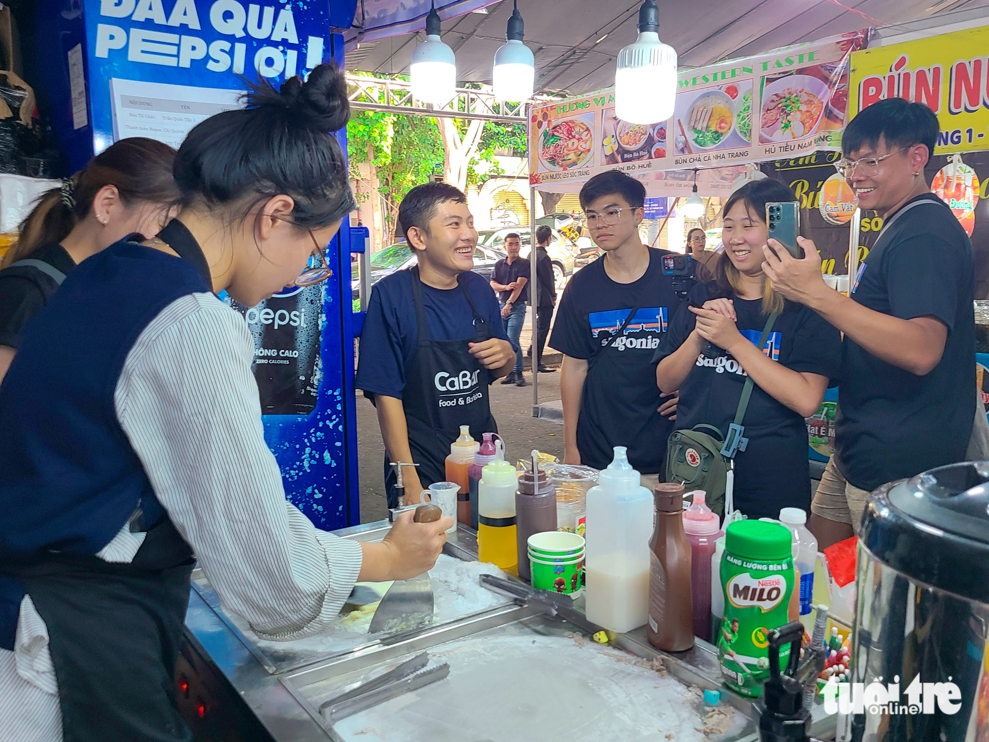 This image shows a group of Singaporean youths excitedly shooting video clips of the making of Thai ice cream at a culinary booth of the Cashless Festival in Ho Chi Minh City on June 16, 2023. Photo: Nhat Xuan / Tuoi Tre