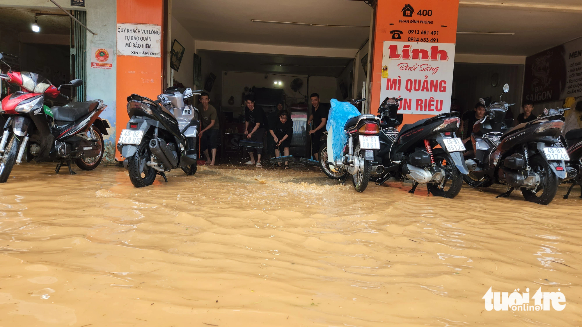 Staff members clean up a flooded eatery in order to offer their services after a heavy rain on June 23, 2023. Photo: M.V. / Tuoi Tre