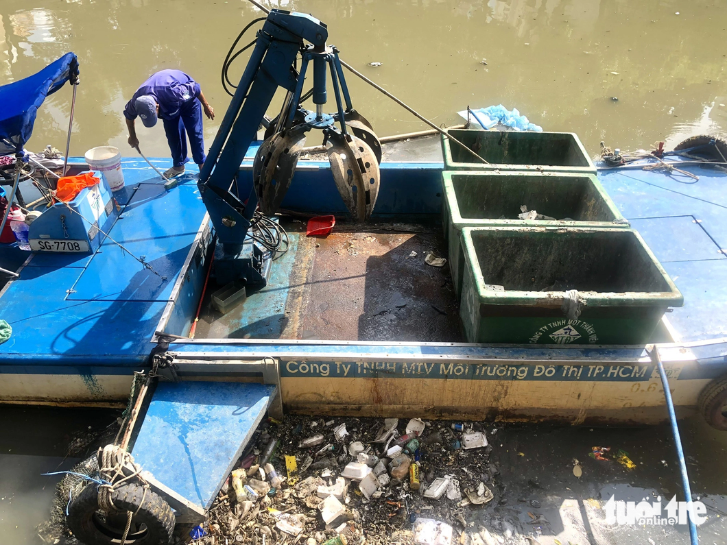 An environmental sanitation worker takes out trash from the canal on June 30, 2023.