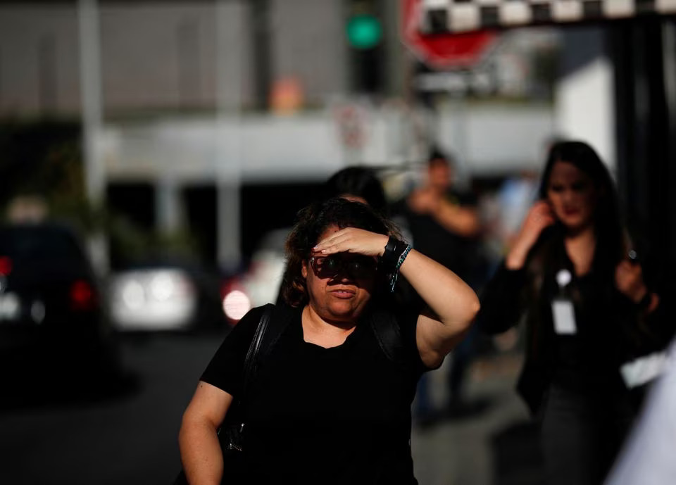 A woman walks along the sidewalk, shielding herself from the sun with her hand as high temperatures continue, in Monterrey, Mexico June 28, 2023. Photo: Reuters