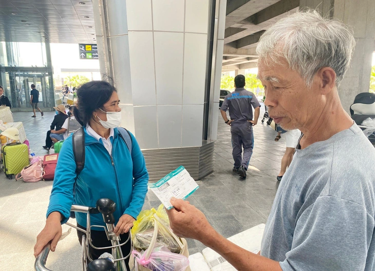 Le Van Quy (R), a 75-year-old resident in Anh Son District, Nghe An Province, receives his luggage after his flight is canceled.