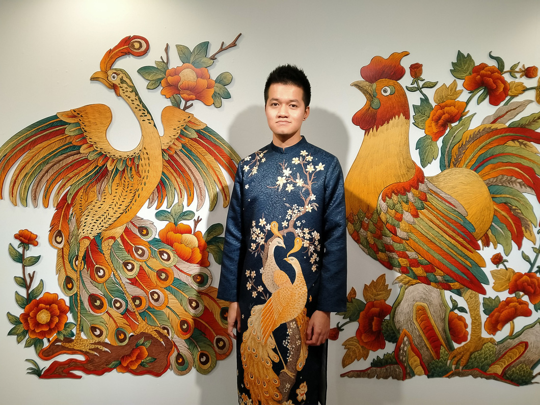 Vietnamese artist Xuan Lam poses for a photo with his ‘Thien ha thai binh’ painting (L). Photo: Thien Dieu / Tuoi Tre