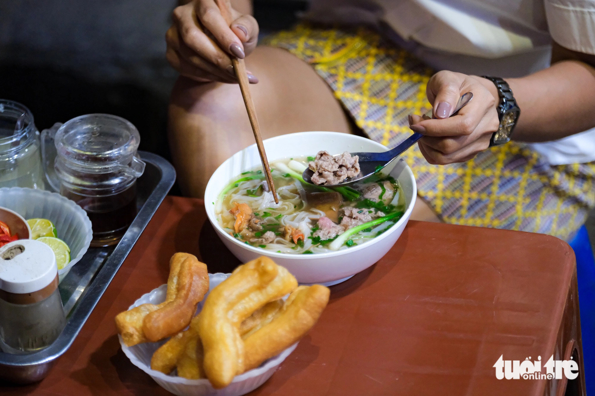 A diner enjoys a bowl of phở (beef/chicken noodle soup), one of Vietnam’s specialties. Photo: Nam Tran / Tuoi Tre