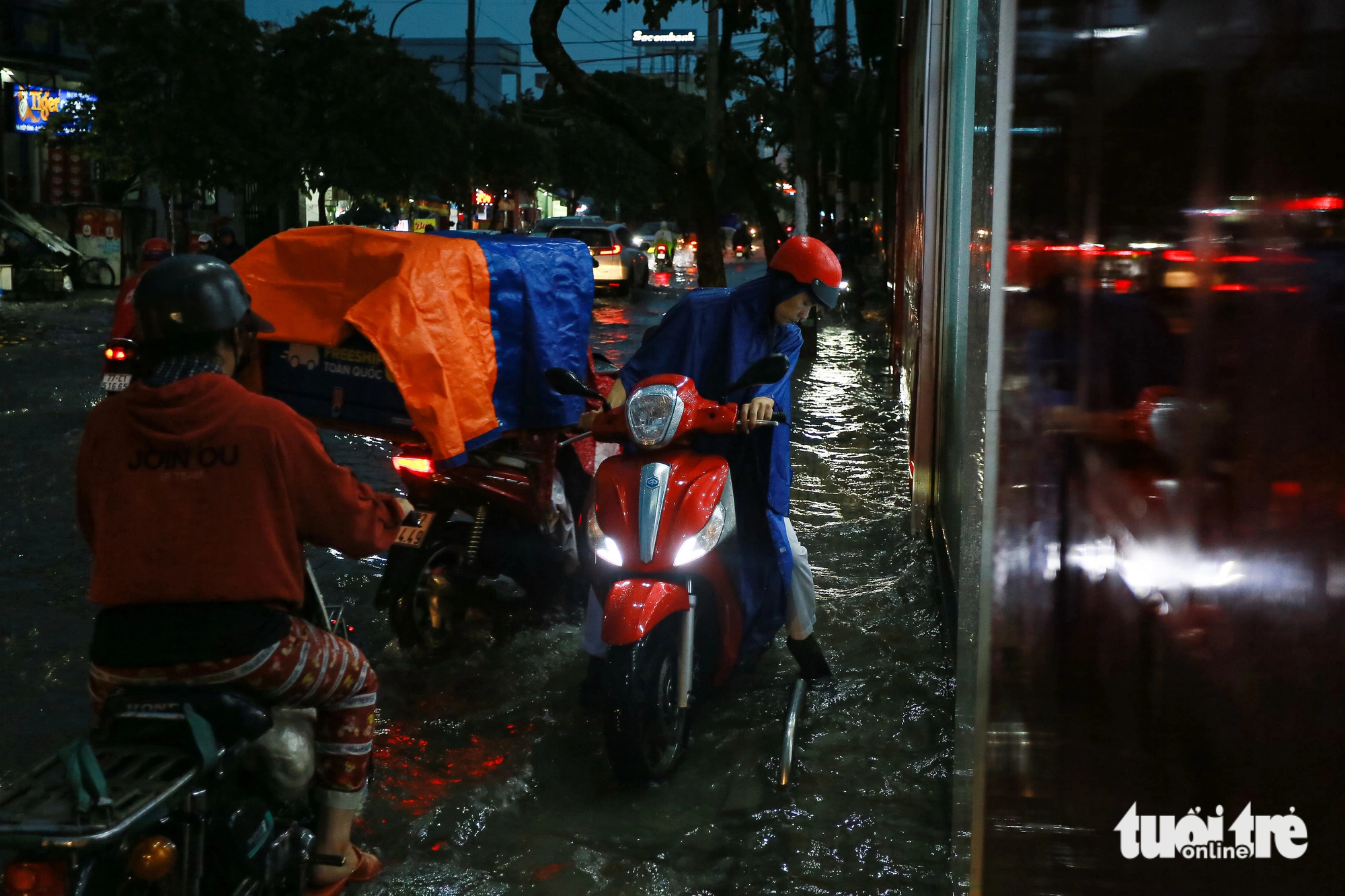 Some motorcyclists travel on the sidewalk on Hiep Binh Street in Ho Chi Minh City’s Thu Duc City to avoid heavily-flooded sections on July 5, 2023. Photo: Chau Tuan / Tuoi Tre