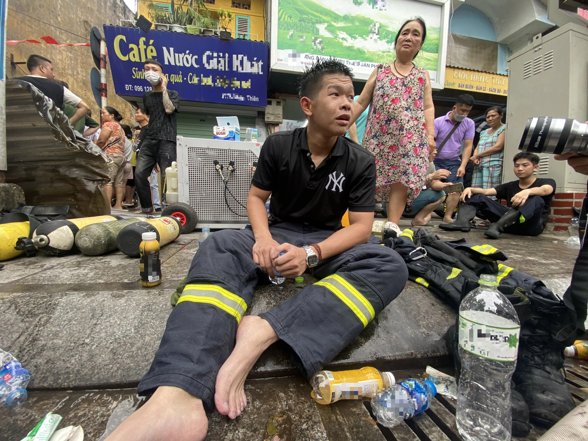 Firefighter Duong Duc Anh takes a break on the sidewalk after joining the fire-fighting and rescue operation. Photo: Chi Tue / Tuoi Tre