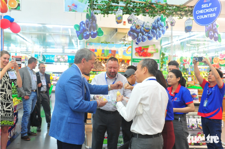 The Governor of the state of Nebraska in the U.S. Jim Pillen (in blue jacket) tries Vietnamese durians. Photo: N.Binh / Tuoi Tre