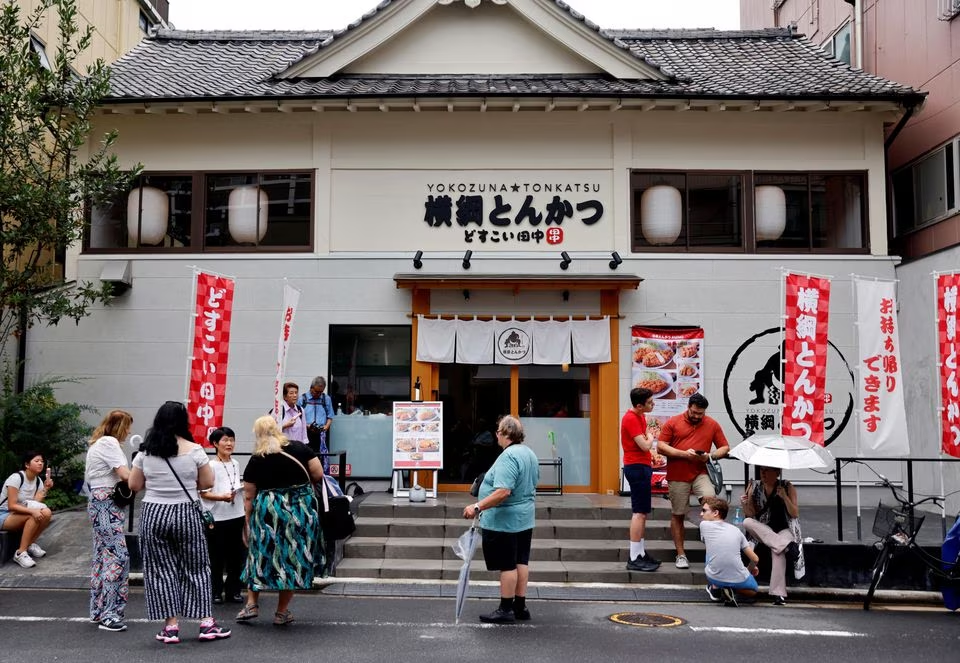 Tourists from abroad wait for Yokozuna Tonkatsu Dosukoi Tanaka, a sumo wrestling themed restaurant to open, in Tokyo, Japan June 30.  Photo: Reuters