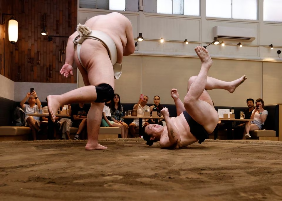 Former sumo wrestlers Kotoohtori, 40, and Towanoyama, 45, engage in sparring on the sumo ring at Yokozuna Tonkatsu Dosukoi Tanaka in Tokyo, Japan June 30. Photo: Reuters