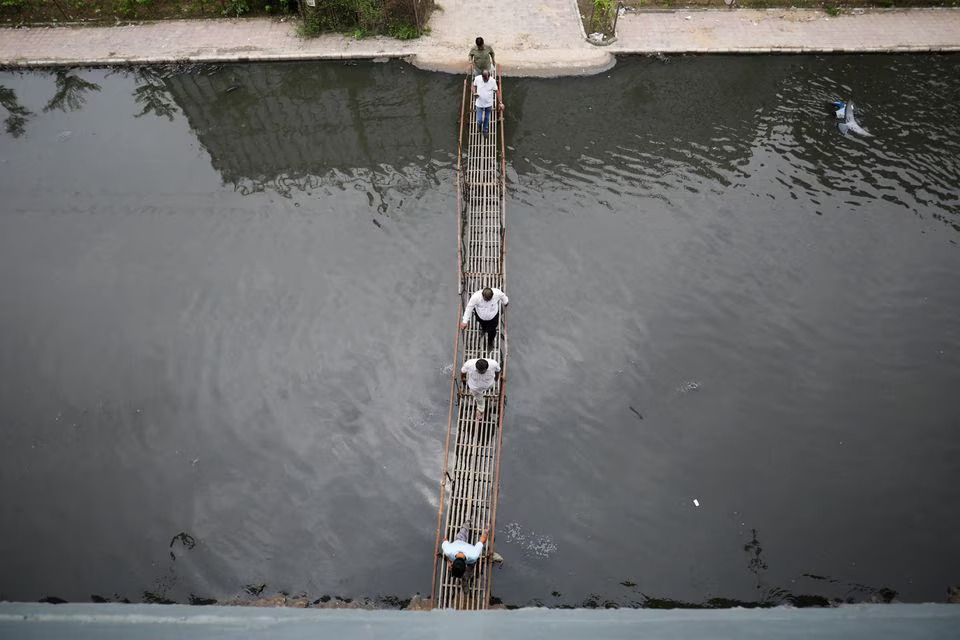 People walk on a makeshift bridge above the waterlogged street in Ahmedabad, India, July 12. Photo: Reuters