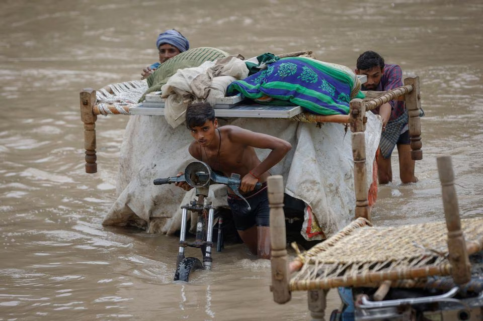 Residents carry their belongings on a rickshaw as they wade through a flooded street in New Delhi, India, July 12. Photo: Reuters