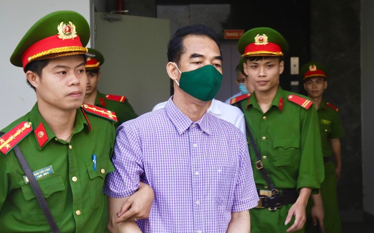 Former Deputy Ministers of Foreign Affairs To Anh Dung (in a checked shirt) is taken to the court in Hanoi. Photo: Danh Trong / Tuoi Tre