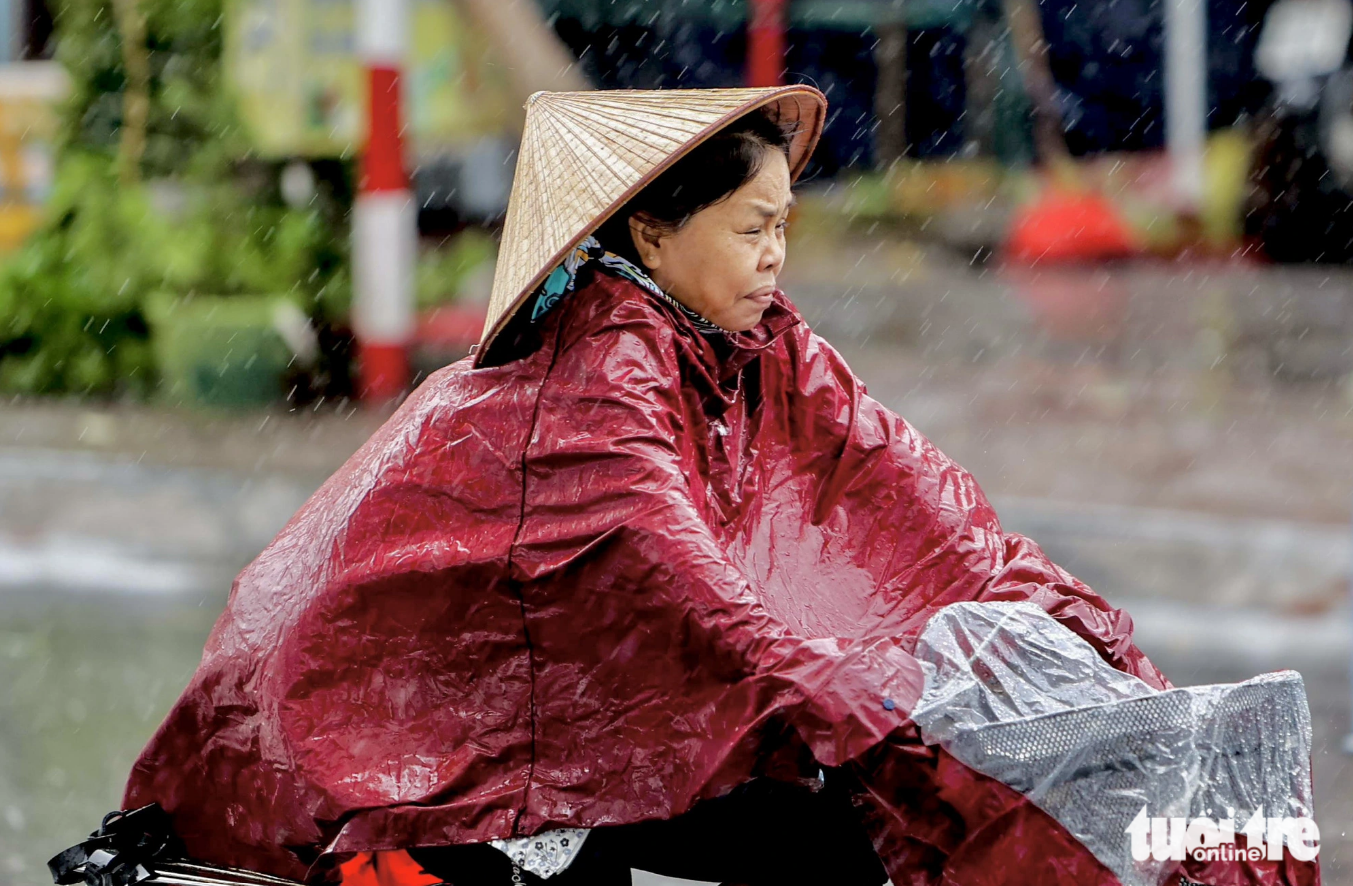 A woman rides her bicycle in the rain in Mong Cai City in Quang Ninh Province, northern Vietnam on July 18, 2023. Photo: Nguyen Khanh / Tuoi Tre