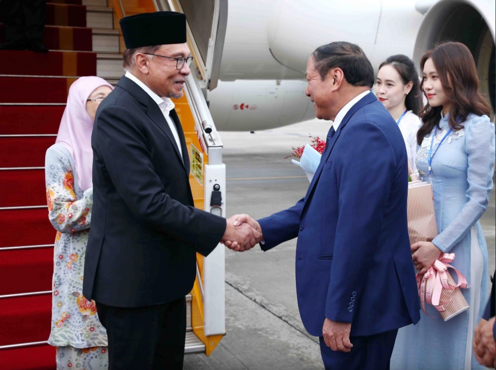 Malaysian Prime Minister Anwar Ibrahim (L) shakes hands with a Vietnamese official upon the former’s arrival at Noi Bai International Airport in Hanoi, July 20, 2023. Photo: Vietnam News Agency