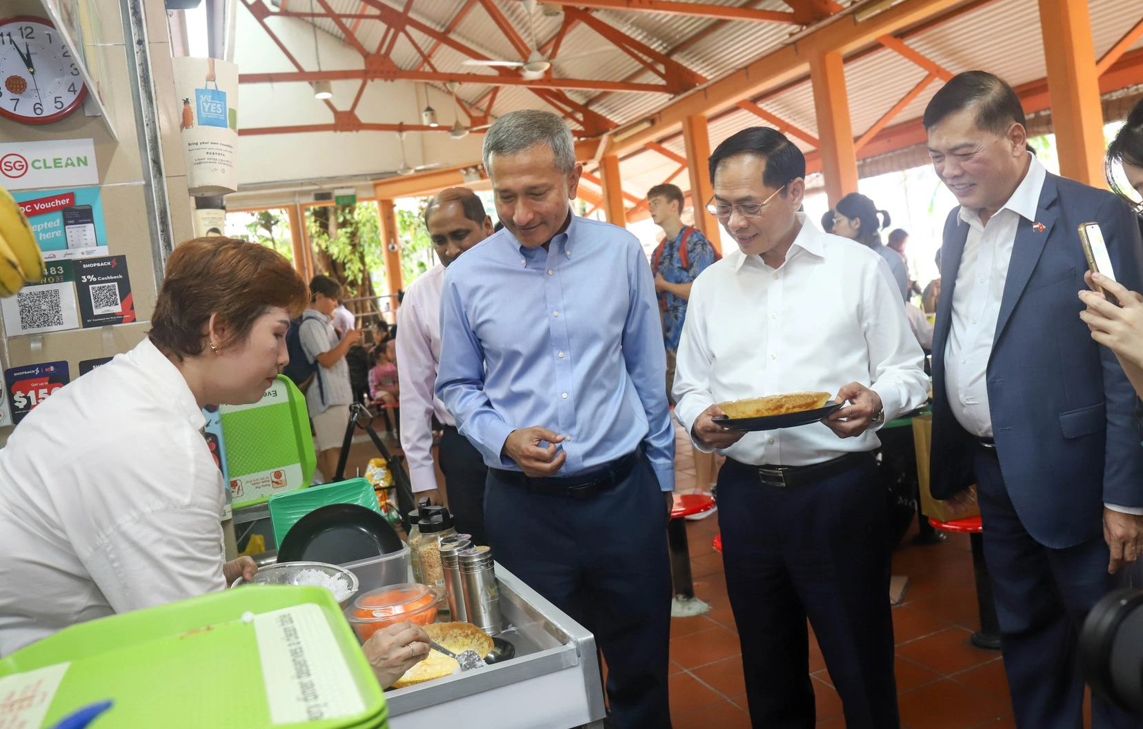 Vietnamese Foreign Minister Bui Thanh Son (R, 2nd) and his Singaporean counterpart Vivian Balakrishnan (R, 3rd) visit a hawker stall run by a Vietnamese national. Photo: P.H