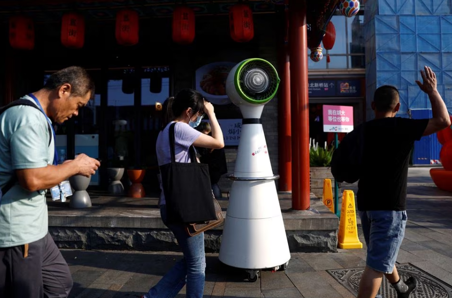 People walk past a misting fan in front of a restaurant amid a yellow alert for heatwave in Beijing, China, July 19, 2023. Photo: Reuters