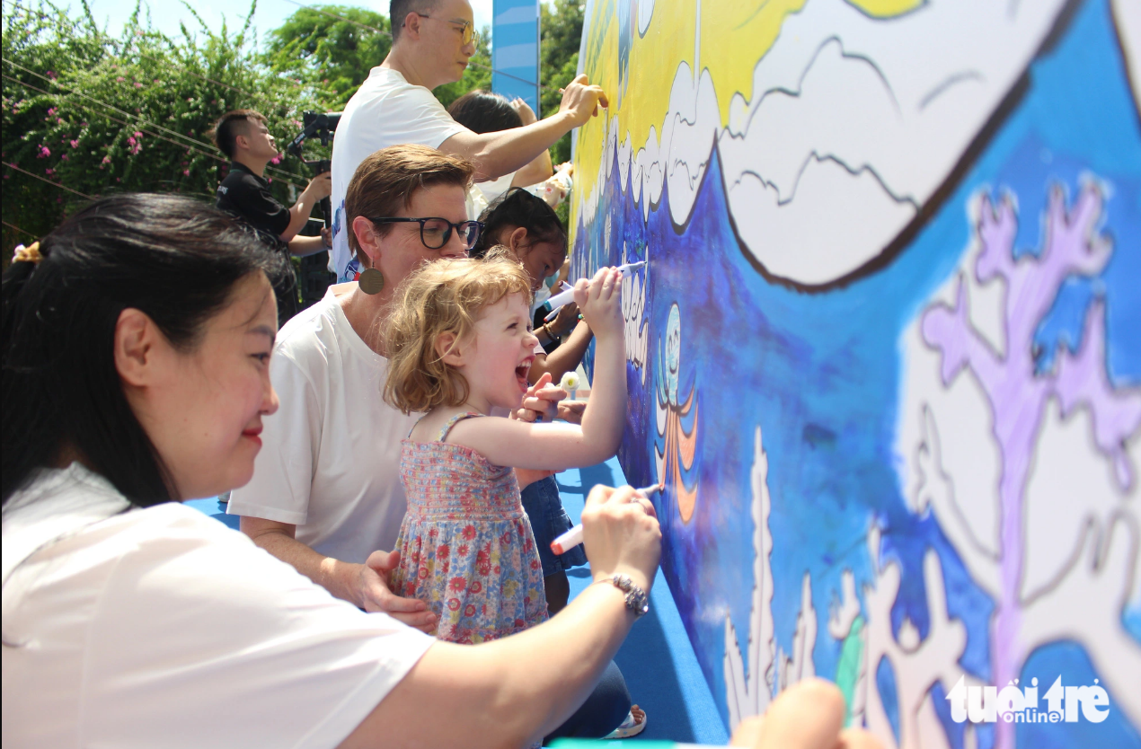 Parents and their kids paint a picture to spread a message of drowning prevention. Photo: Duong Lieu / Tuoi Tre