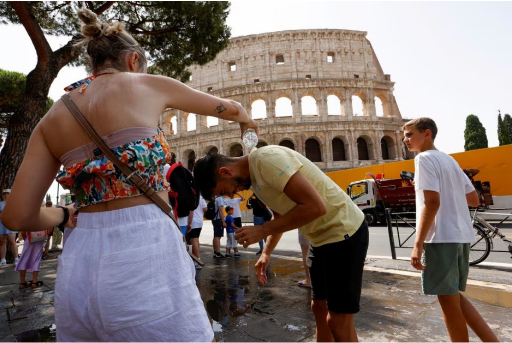 A woman pours water on a man near the Colosseum during a heatwave across Italy, in Rome, Italy. July 18, 2023. Photo: Reuters