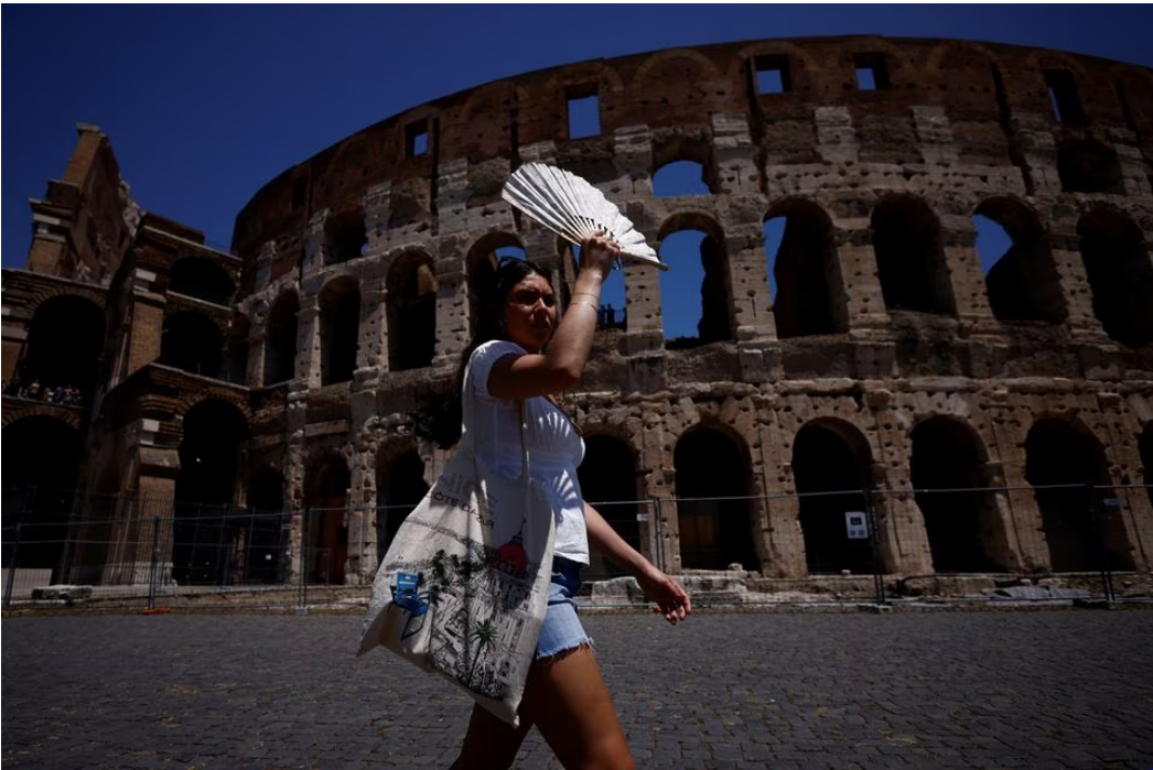 Michelle from the U.S. uses a fan to shelter from the sun near the Colosseum during a heatwave across Italy, in Rome, Italy July 11, 2023. Photo: Reuters