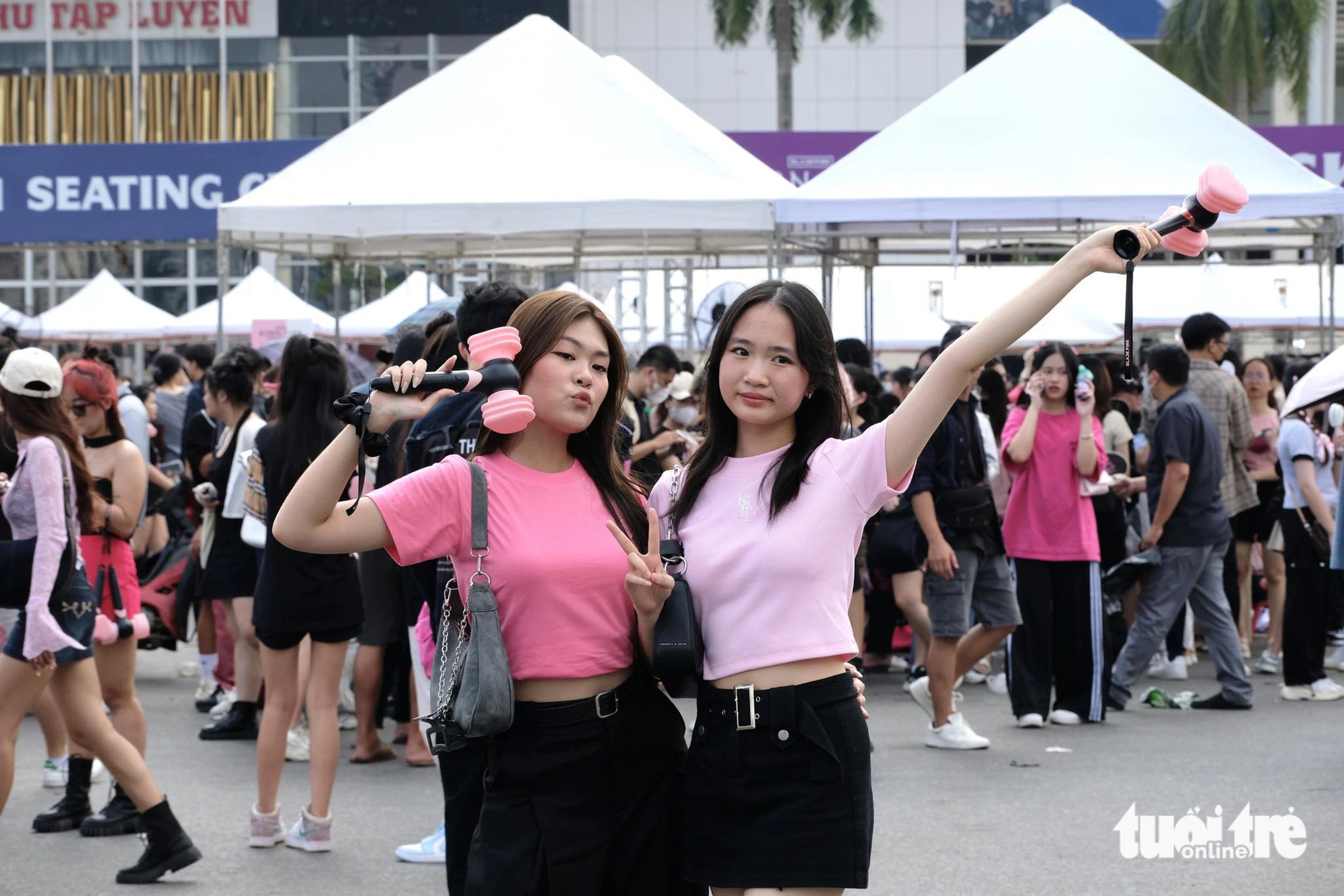 Two girls holding black and pink hammer-looking light sticks pose for a group photo at the Hanoi-based My Dinh National Stadium before the show. Photo: Nguyen Bao / Tuoi Tre
