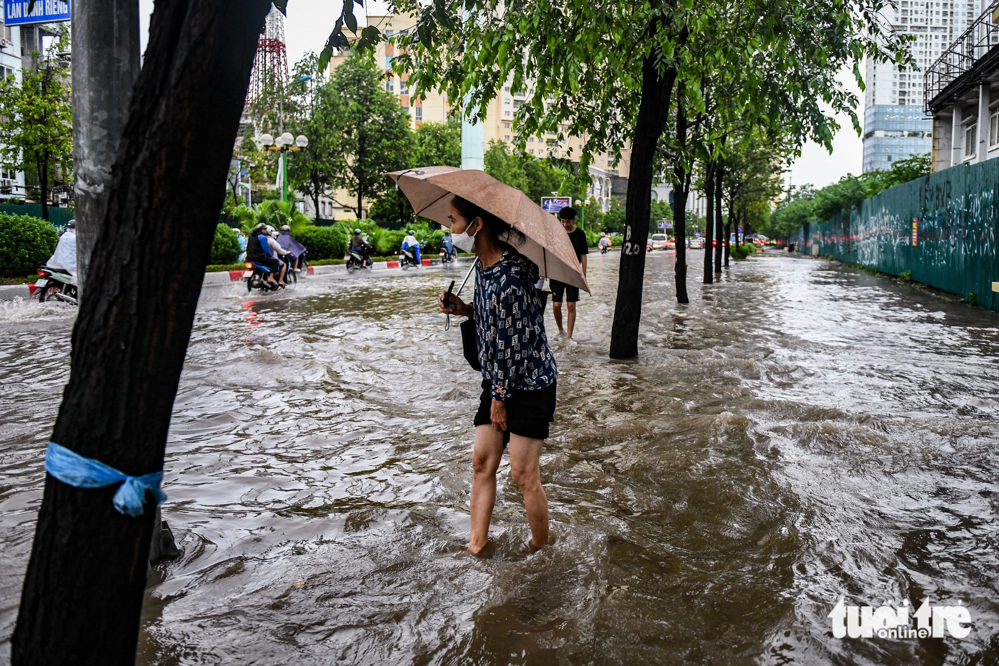 Rainwater submerges the roadbed and sidewalks of Le Van Luong Street. Photo: Nam Tran / Tuoi Tre