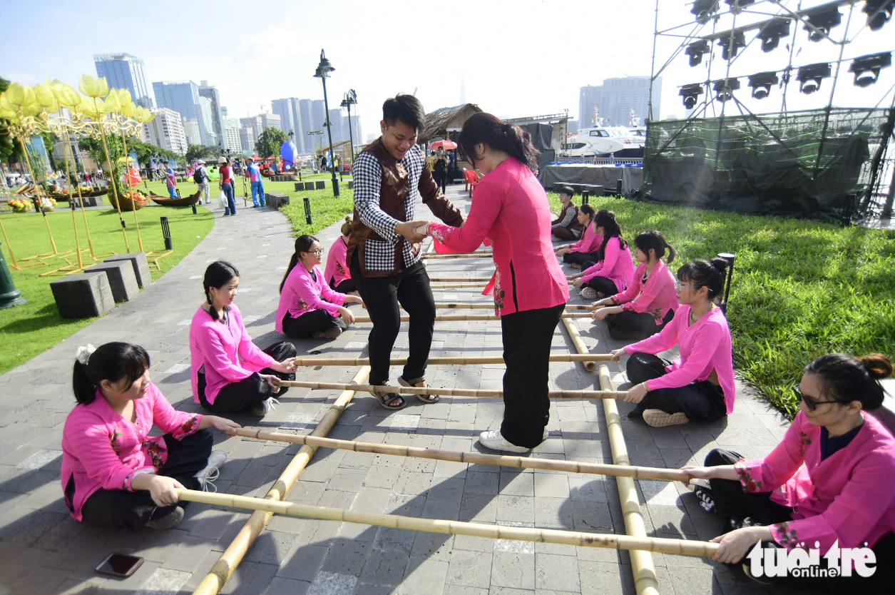 An artist teaches cheraw dance to a visitor at the Bach Dang Wharf Park in downtown Ho Chi Minh City during the river festival. Photo: Quang Dinh / Tuoi Tre