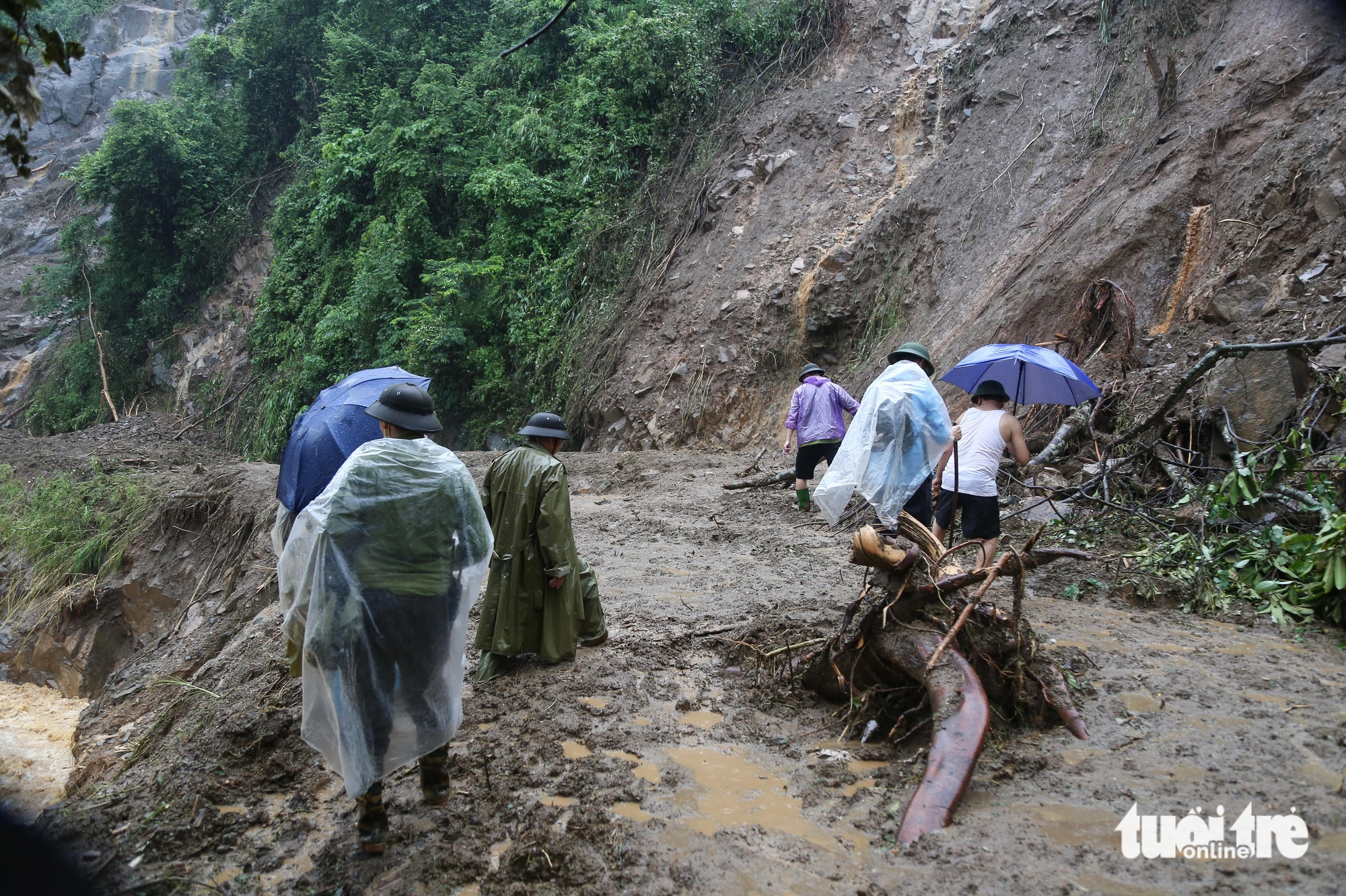 Competent forces and local residents have to go through muddy water puddles and landslide-hit areas to approach Ho Bon Commune. Photo: Chi Tue / Tuoi Tre