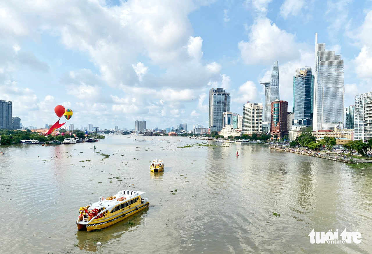 A photo shows a water bus traveling on the Saigon River with landmark buildings in the background. Photo: Tu Trung / Tuoi Tre