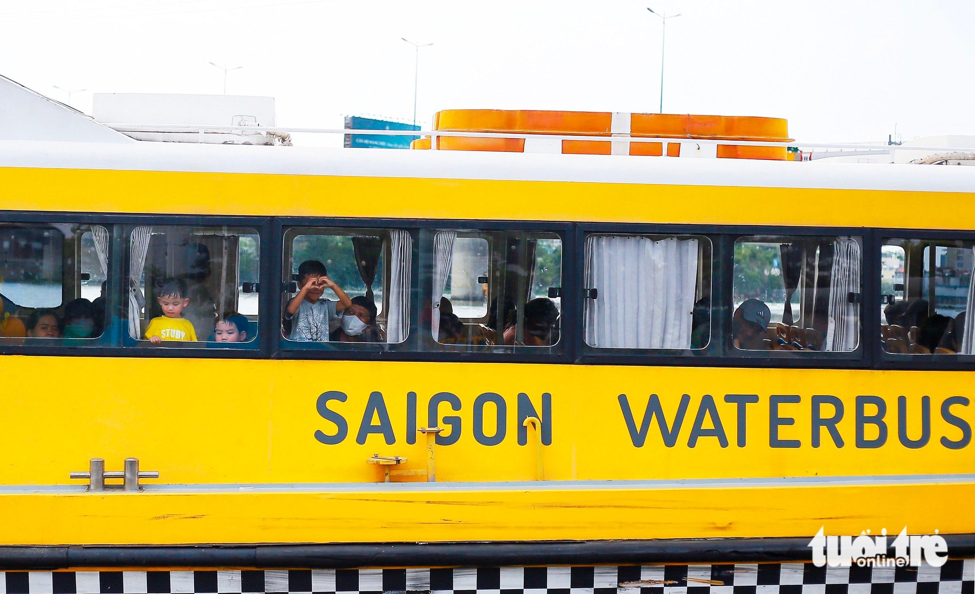 Children view through windows while traveling by a water bus on Saigon River in Ho Chi Minh City. Photo: Chau Tuan / Tuoi Tre