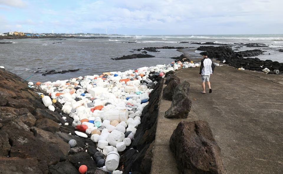 A man looks at plastic waste after typhoon Khanun's passing at a port on Jeju island, South Korea, August 10, 2023. Yonhap via Reuters