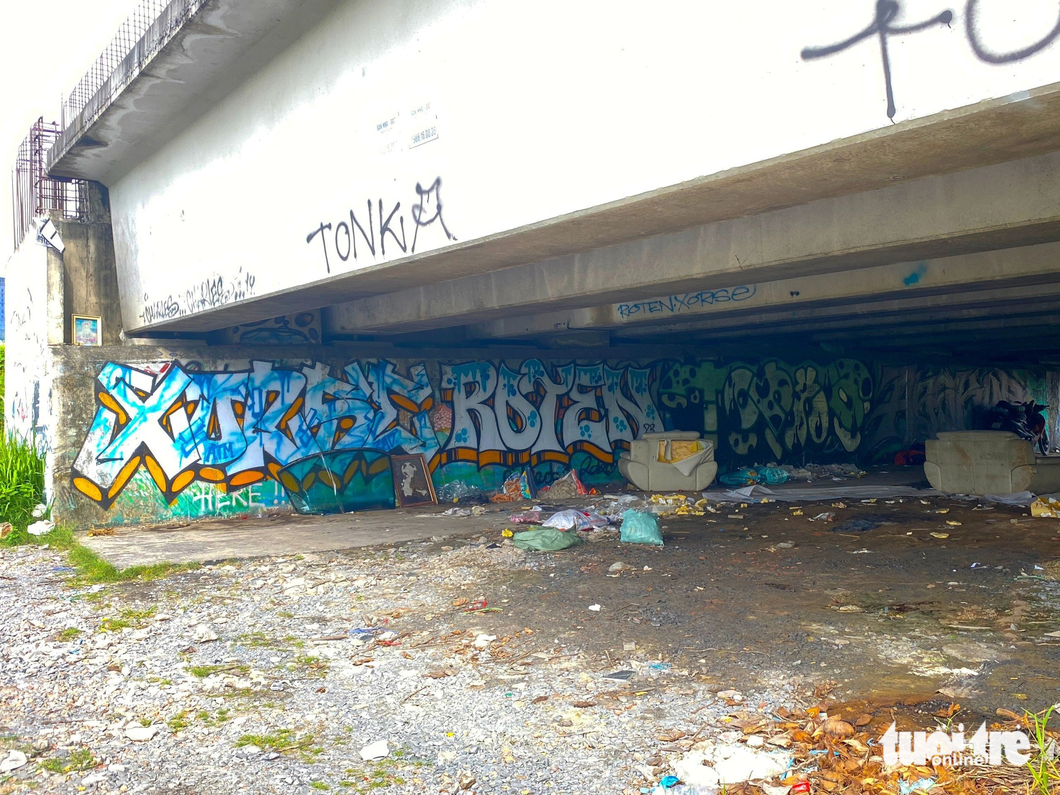 Vandalizing paint and graffiti fill a wall under the bridge.