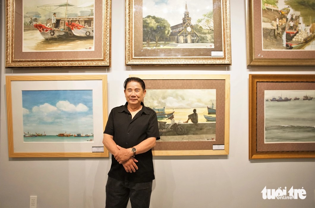 Artist Hong Quan stands in front of his watercolors at the exhibition. Photo: Huynh Vy / Tuoi Tre