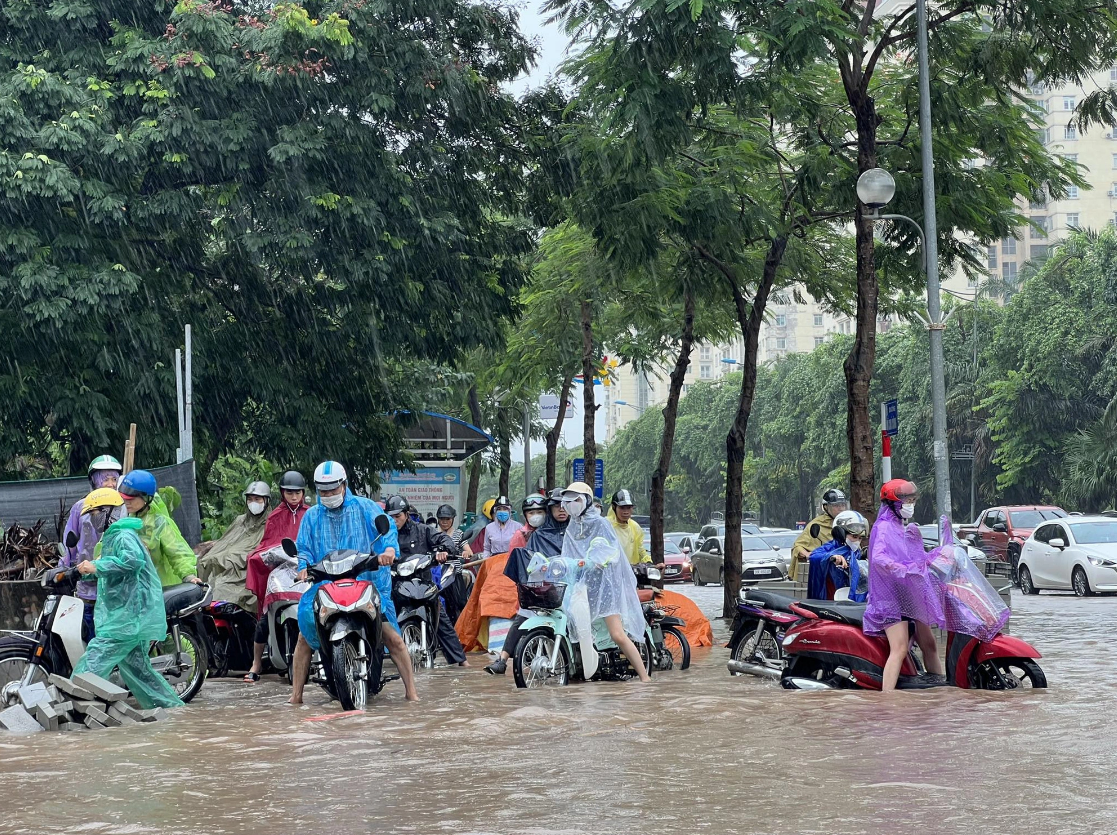 Many commuters are struggling with an inundated street in Hanoi. Photo: Pham Tuan / Tuoi Tre