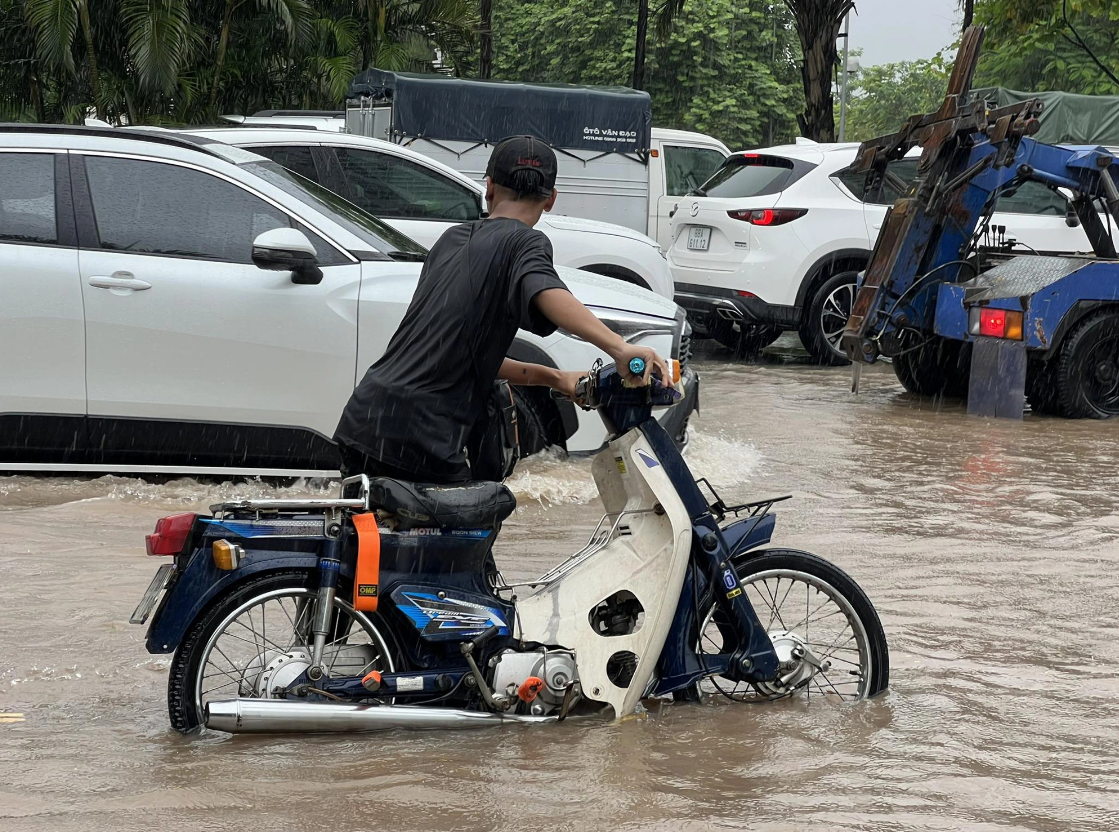A man is picturing wading through a heavily flooded section of Vo Chi Cong Street in Hanoi. Photo: Pham Tuan / Tuoi Tre