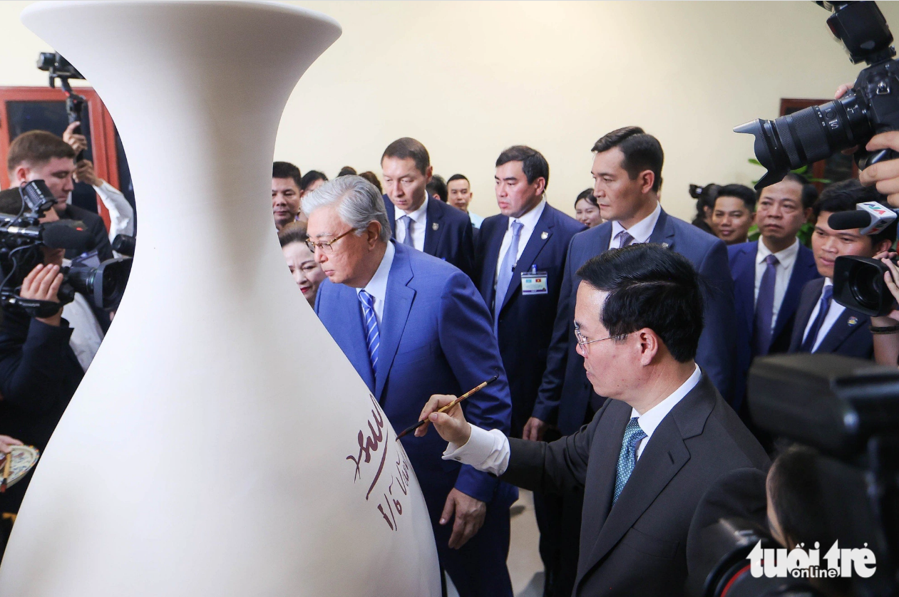 The two presidents of Vietnam and Kazakhstan sign their names on a big vase. Photo: Nguyen Khanh / Tuoi Tre