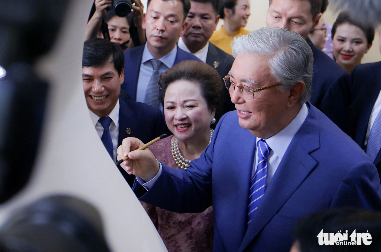 Kazakh President Kassym-Jomart Tokayev signs on a vase, a piece of pottery in Chu Dau Pottery Village. Photo: Nguyen Khanh / Tuoi Tre