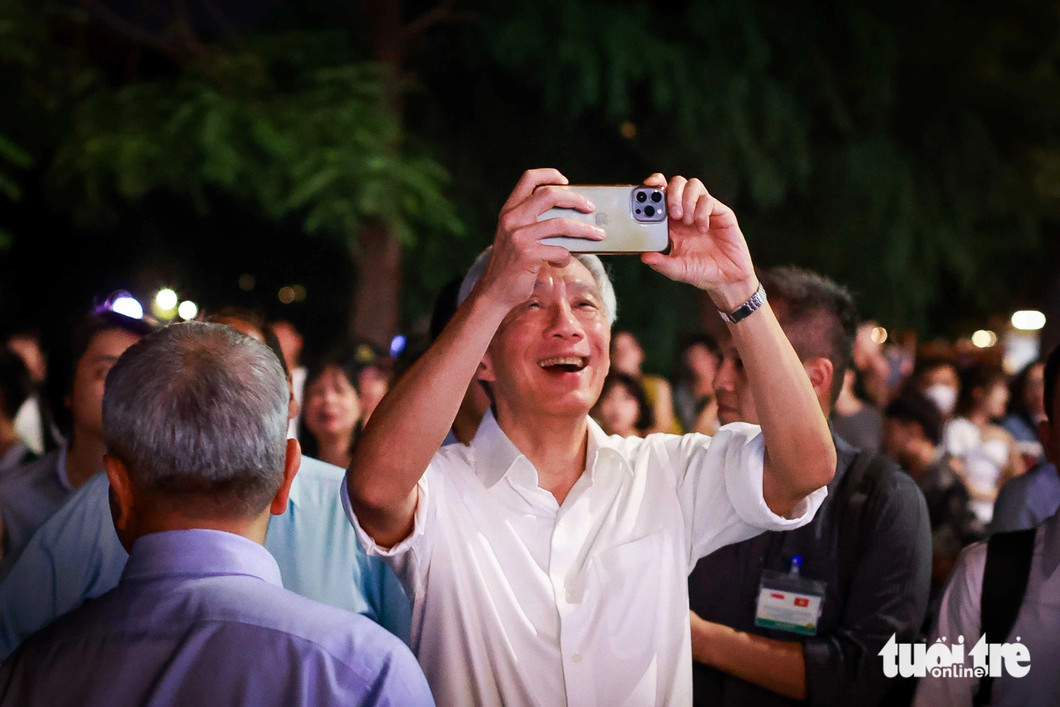 Singaporean PM Lee Hsien Loong is seen happily taking photos during his walking tour of Hoan Kiem Lake in Hanoi, Vietnam, on the evening of August 27, 2023. Photo:  Nguyen Khanh / Tuoi Tre